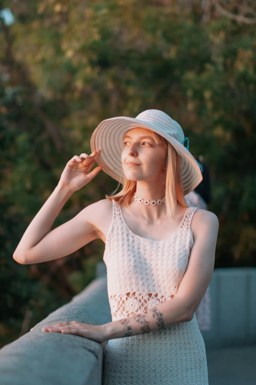 a young woman poses in a hat on the beach