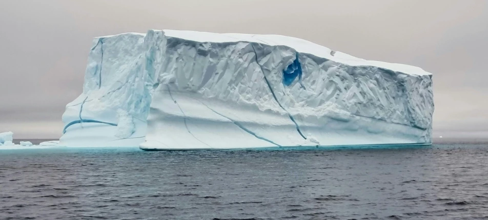an iceberg in a body of water on a cloudy day