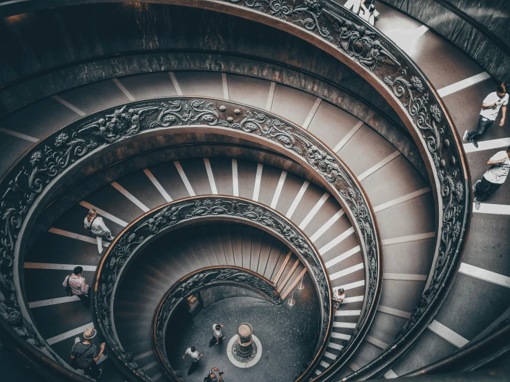 three people walk on the top spiral staircase