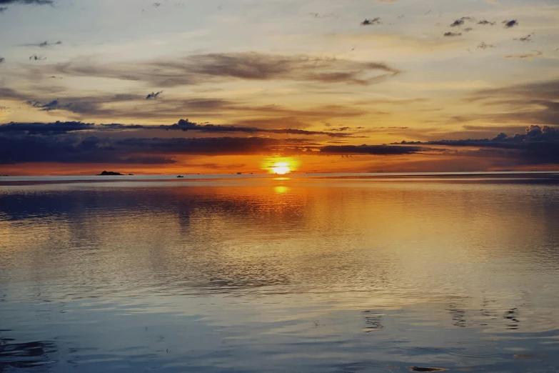 the setting sun is setting over the horizon of a bay