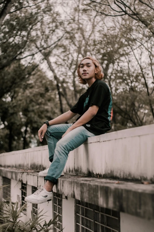 a young man sitting on the side of a wall