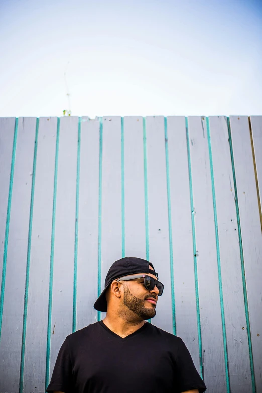 the man is posing against a wall wearing his eye glasses