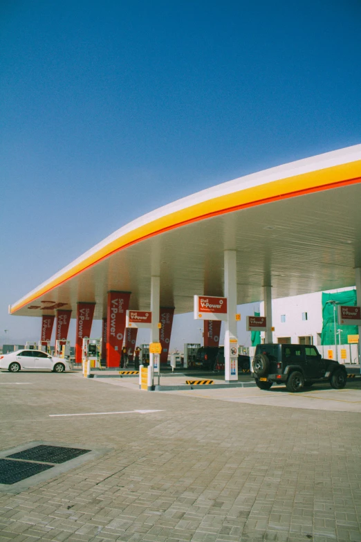 some cars parked by a gas station with a large sign