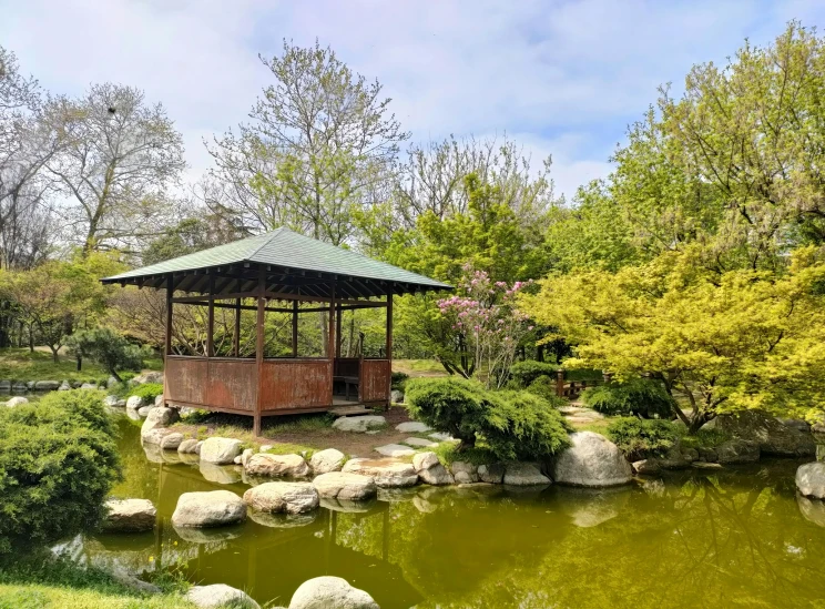 a small pavilion in a park surrounded by water and trees