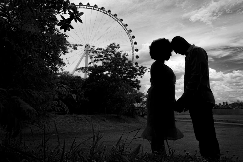 a couple are in front of a ferris wheel