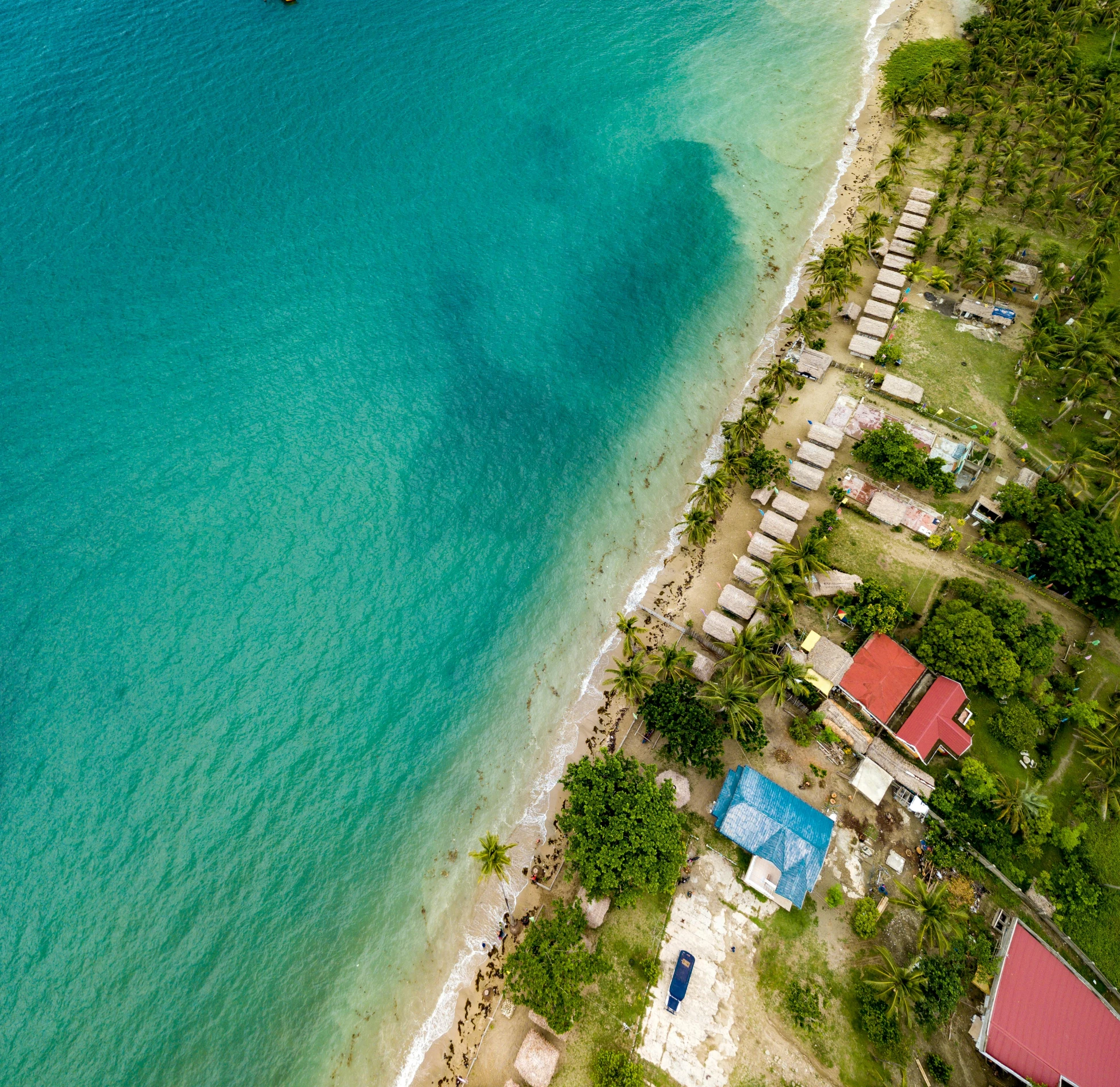 an aerial view of a boat moored in clear blue water next to a beach