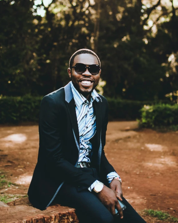 a man wearing glasses is sitting on a log