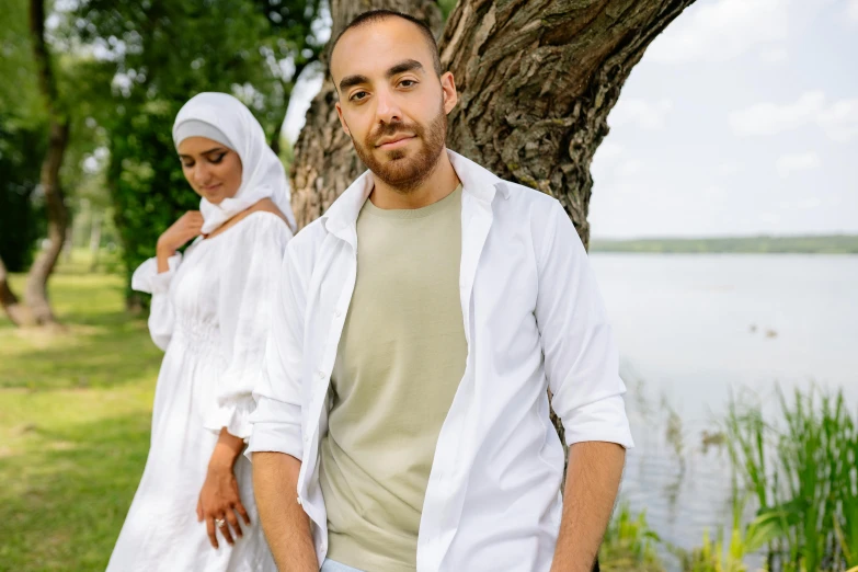 a man and woman standing next to a tree