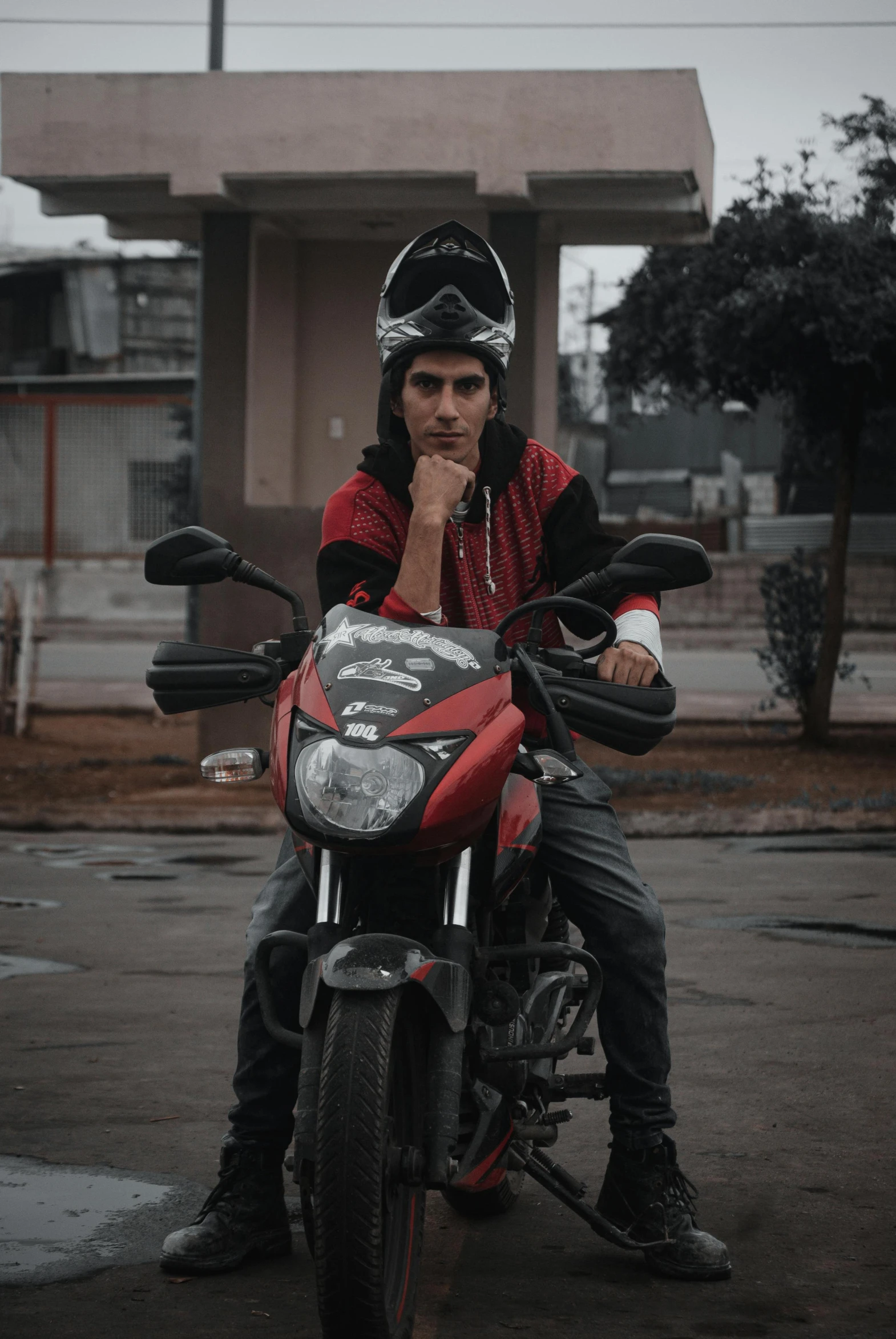 man sitting on motorcycle with red leather outfit and black helmet