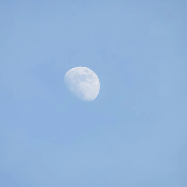 the moon is visible in a clear blue sky