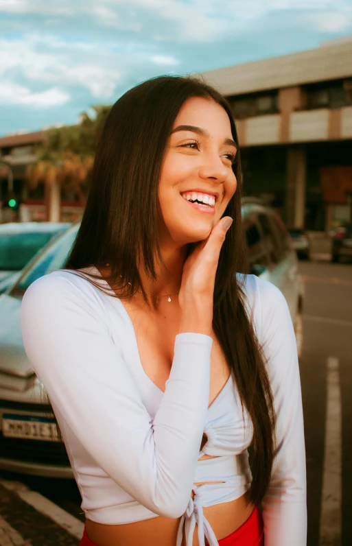 a woman is smiling at soing outside near a parking lot