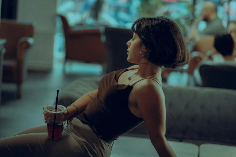 the woman sits in a chair while holding a drink