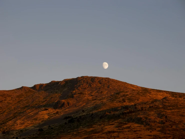 a small moon is seen in the sky above a mountain