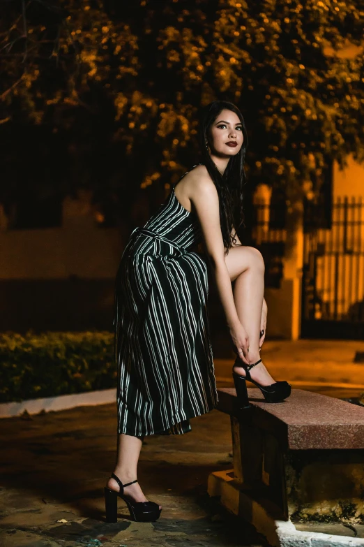 a woman sitting on a bench wearing sandals at night