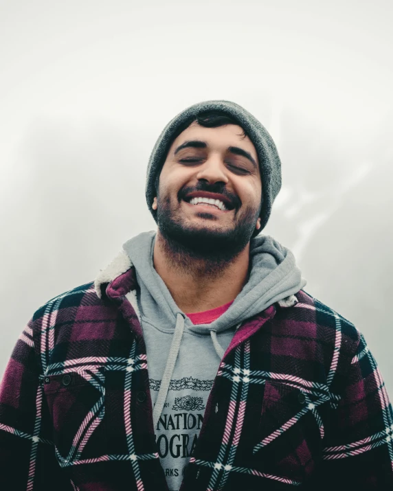 a man in a hooded jacket smiling and wearing a hoodie