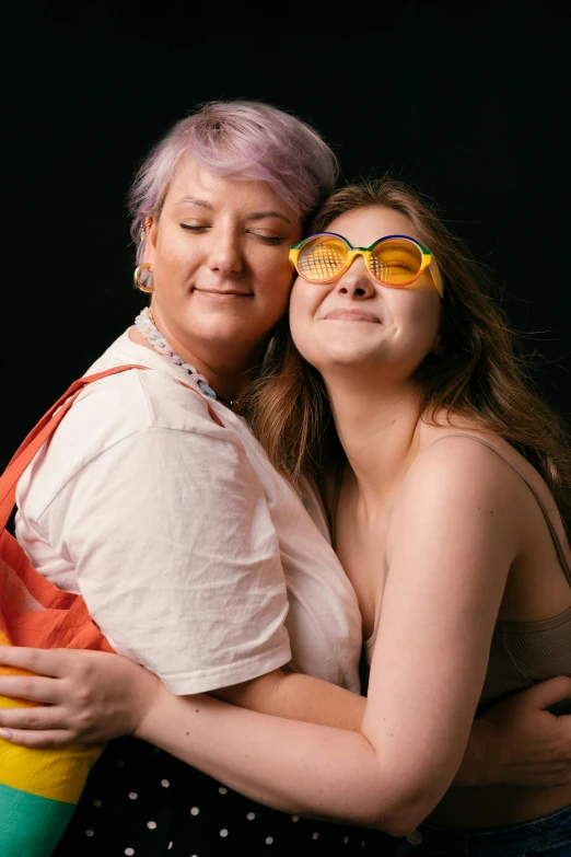 two women with different colored glasses hugging