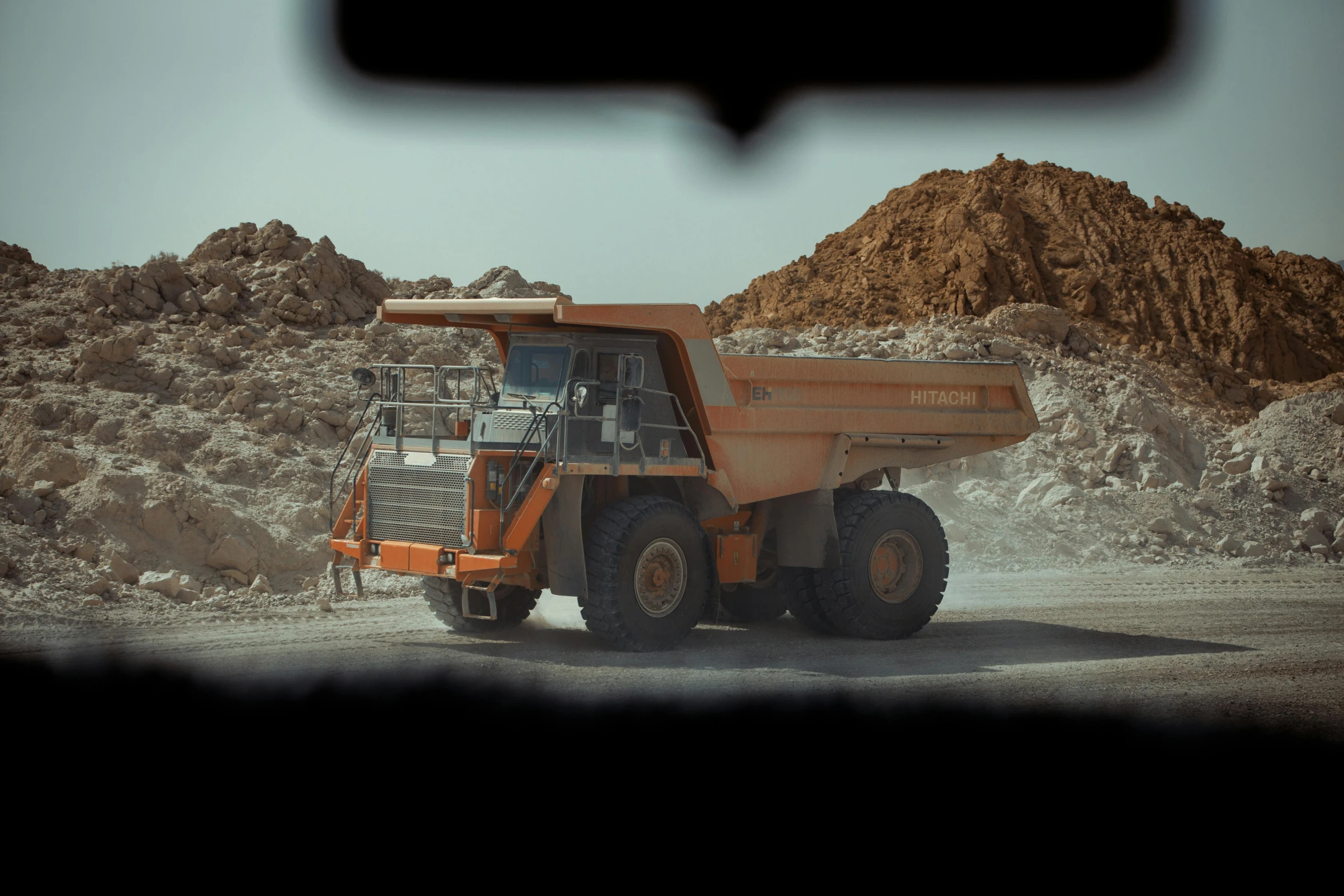 a dump truck is traveling around a gravel road