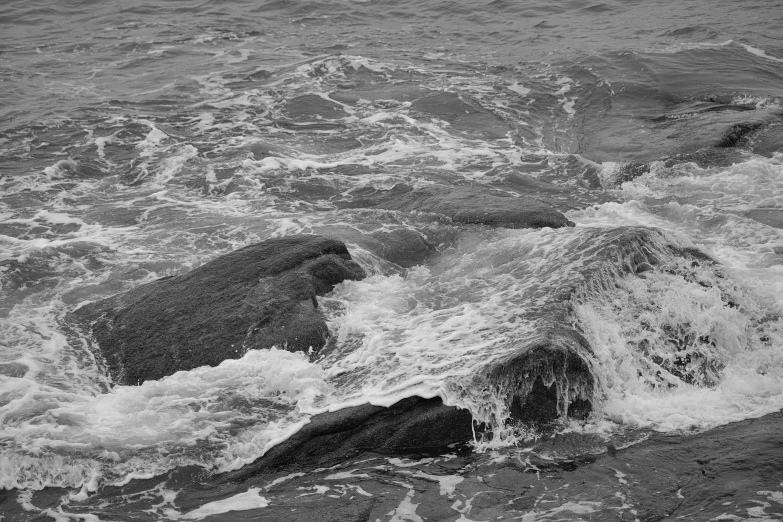 some water splashing on rocks in the middle of the ocean