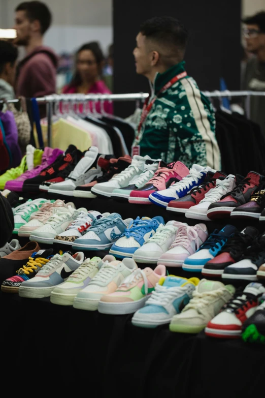 a man standing behind a table full of sneakers