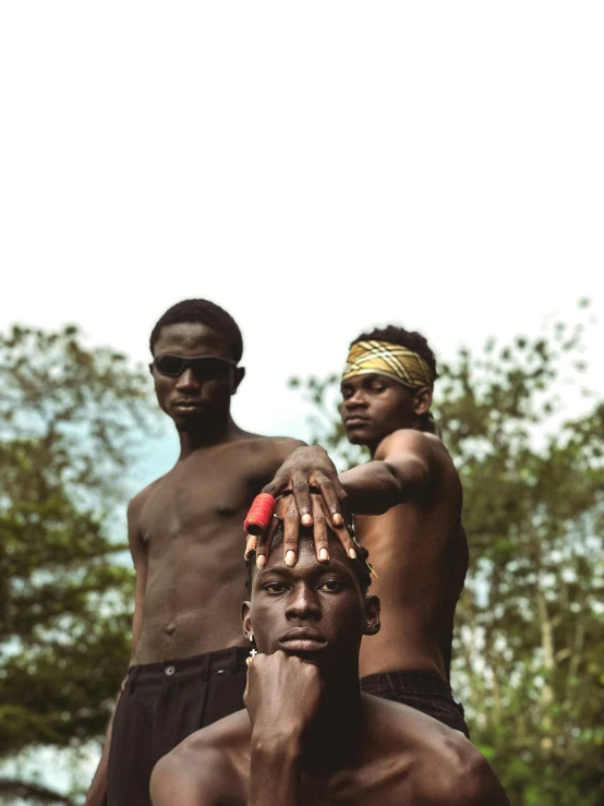 three young men with different colored eyes holding the tip of their hands