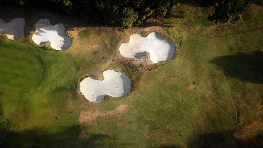 four mounds in a grass covered golf course with one large hole