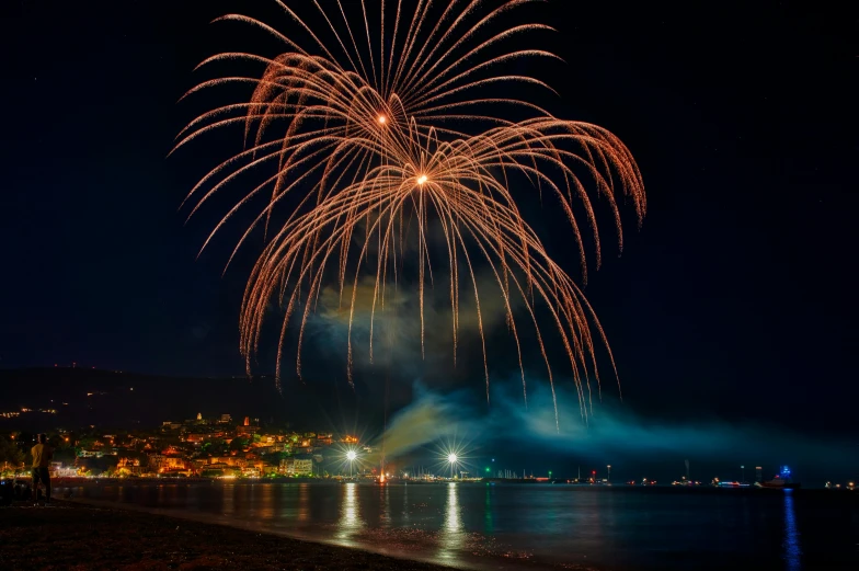 a colorful fireworks display on the water near beach