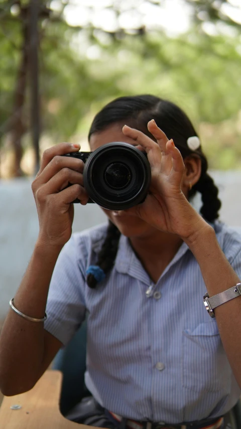 woman in dress shirt taking picture from behind camera with phone