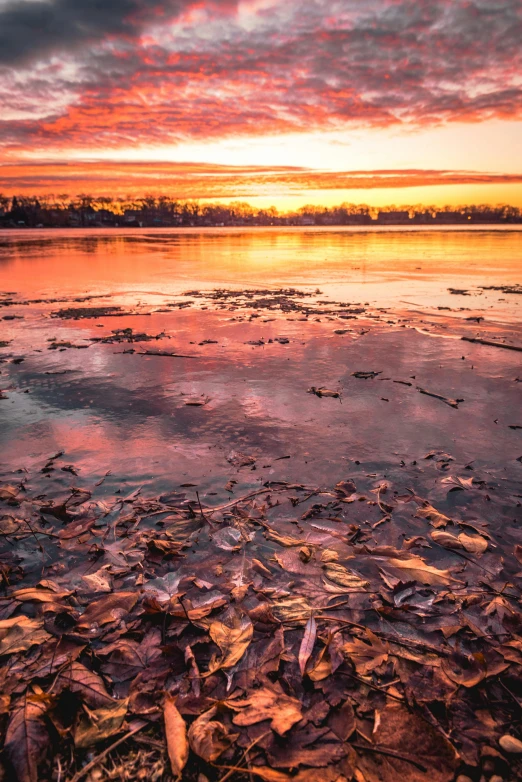 the sky is red and cloudy at a very small lake