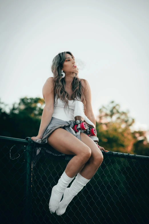 woman sitting on top of fence holding a cigarette