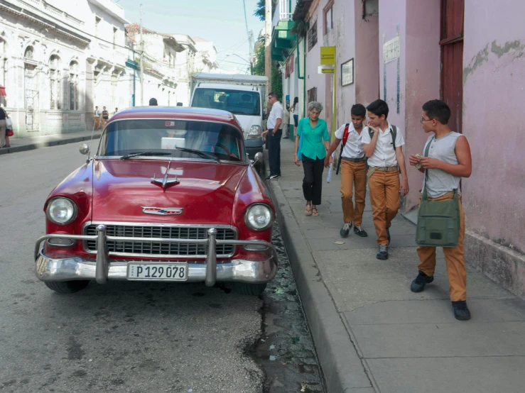 men walk down the street past a car with people in it