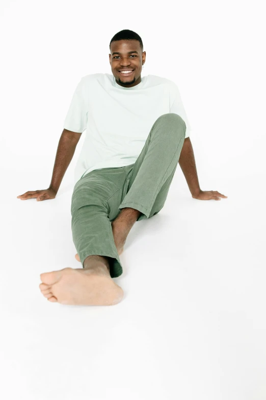 a young man poses in green pants and white shirt