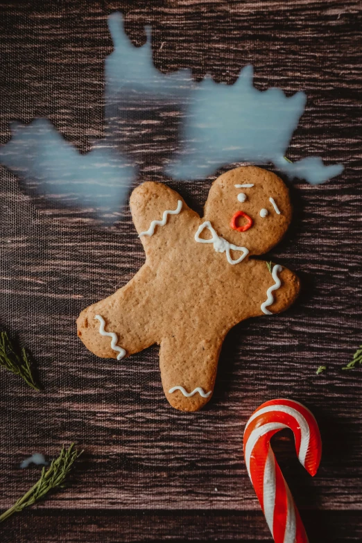 an overhead view of a gingerbread ornament with candy cane on a table