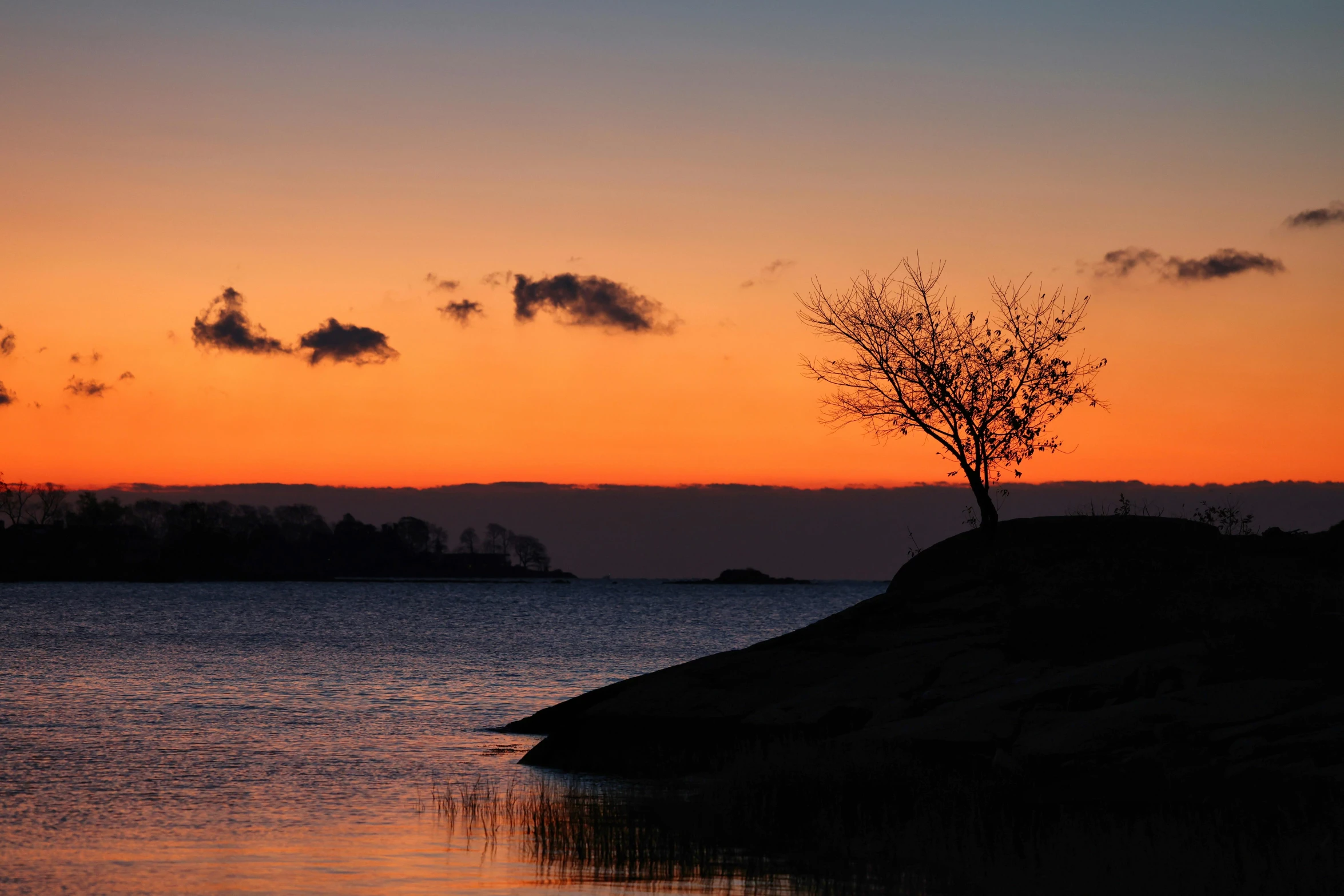 the sky is orange and red above the water