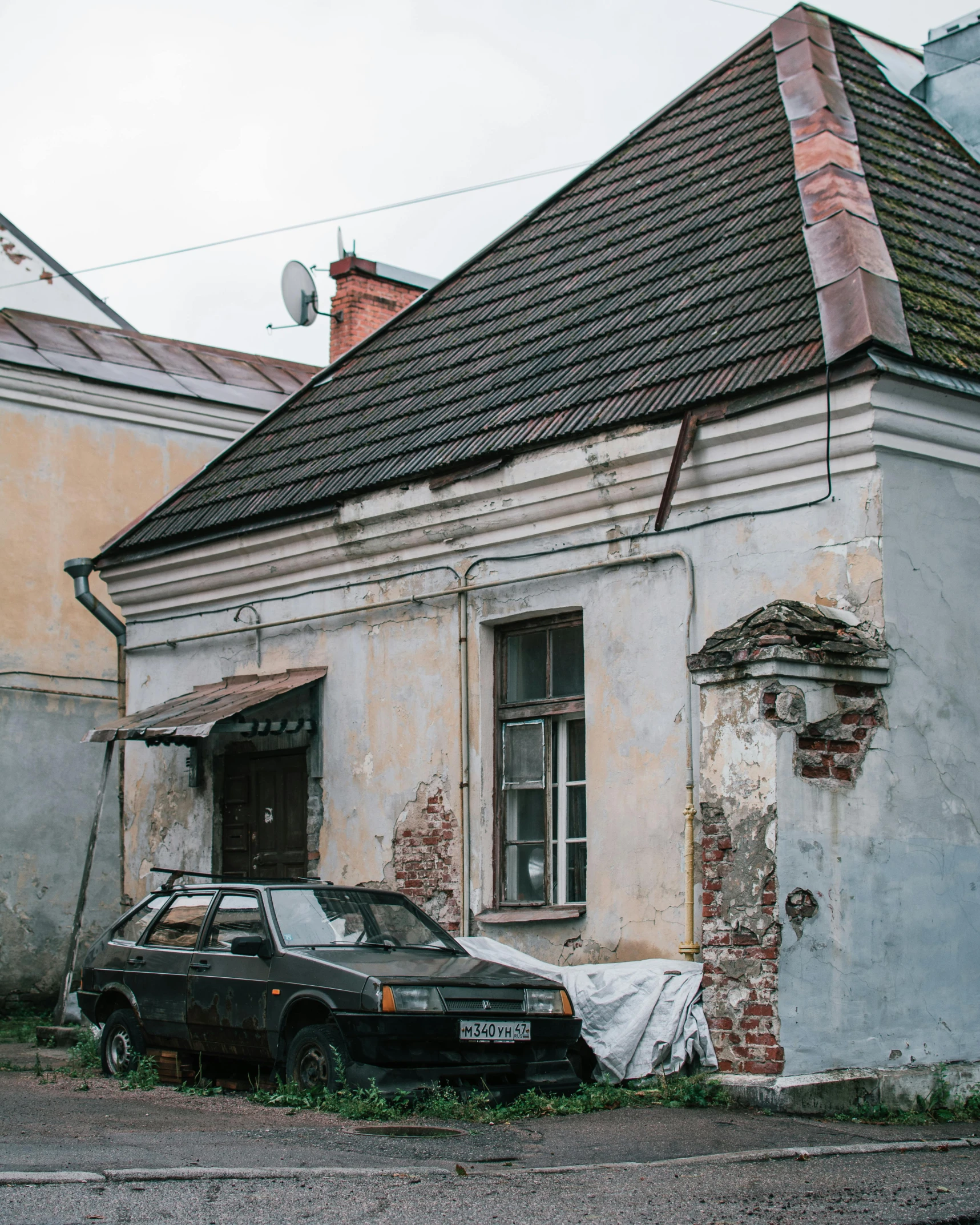 there is an old car parked in front of a dilapidated building