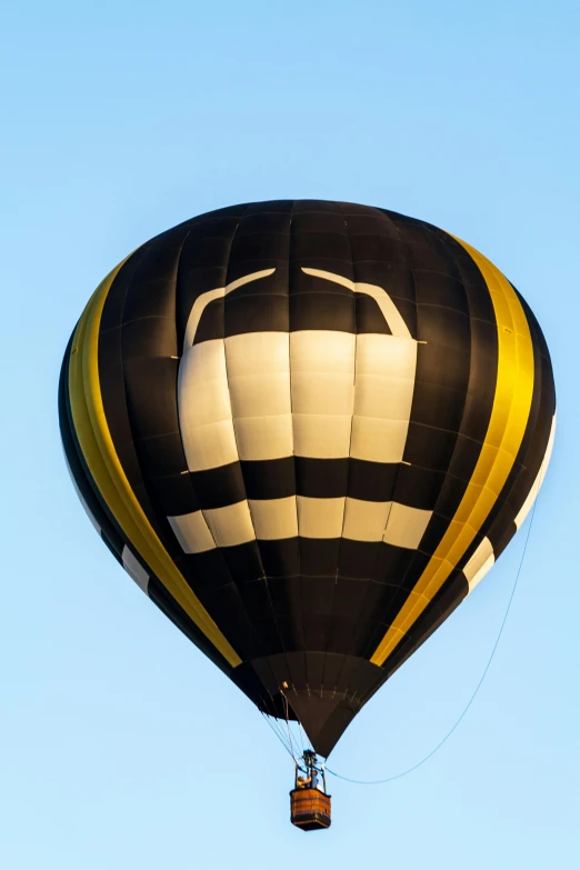 a black, white and yellow  air balloon flying in the sky