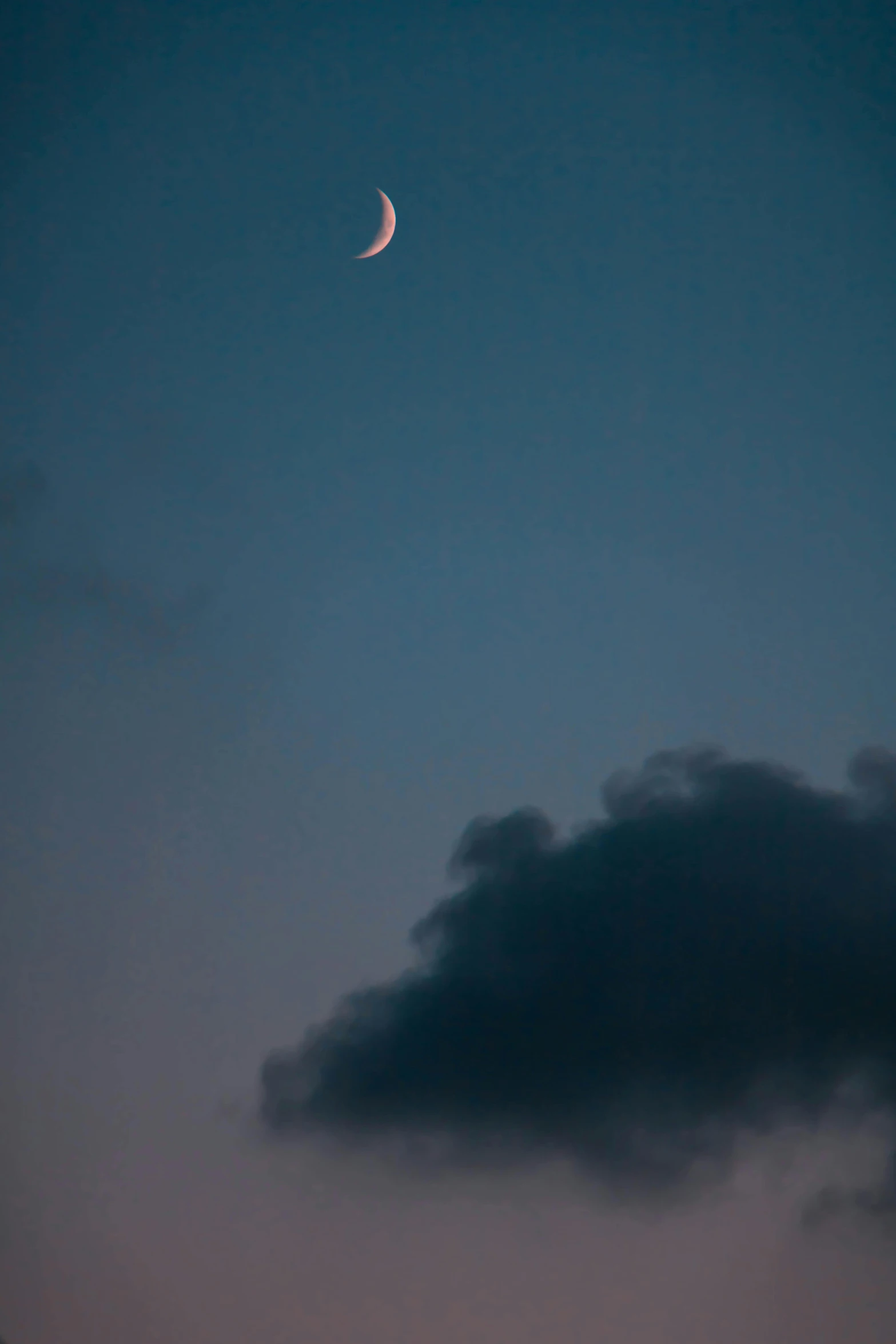 a cloud covered sky with an orange crescent