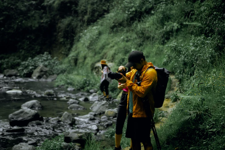 a person taking a po with his camera next to a stream