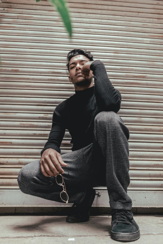 a young man sitting on a ledge leaning against a wall and making a call