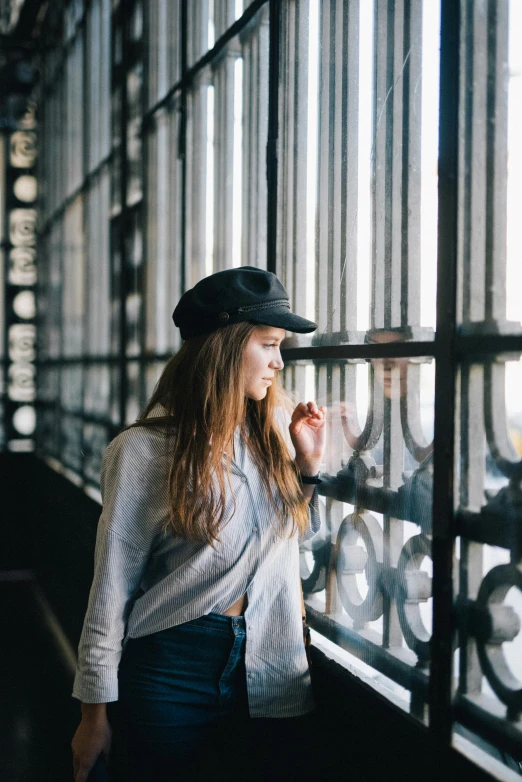 woman leaning on fence looking outside with hat