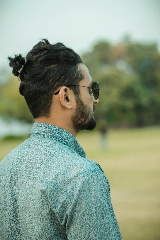 a man wearing sunglasses stands and stares up to the right