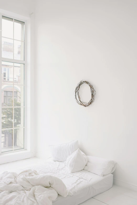 a bed with white sheets is beside a wall
