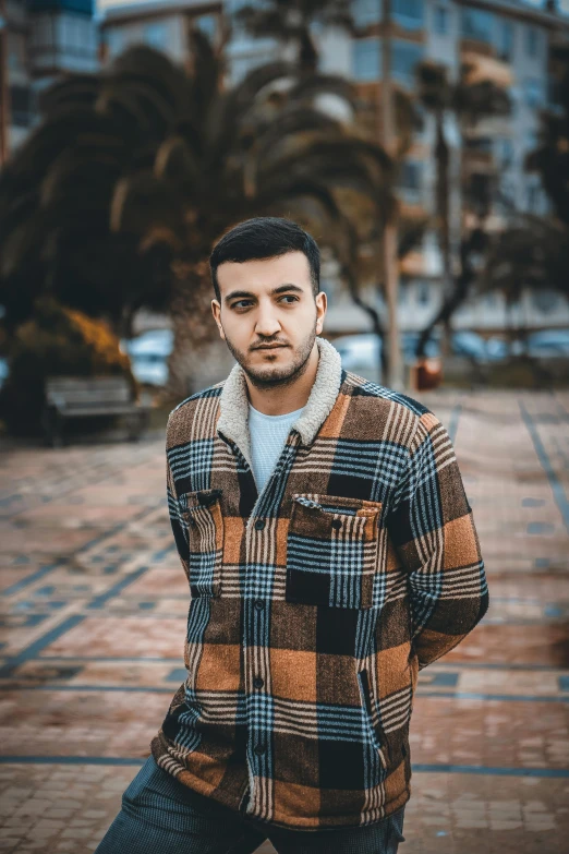 man standing in the street wearing a flannel plaid jacket and jeans