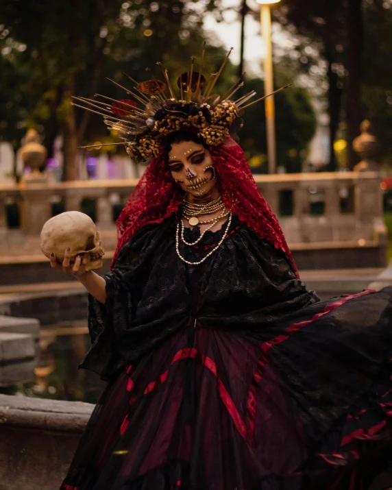 a woman wearing a costume while holding a small skull