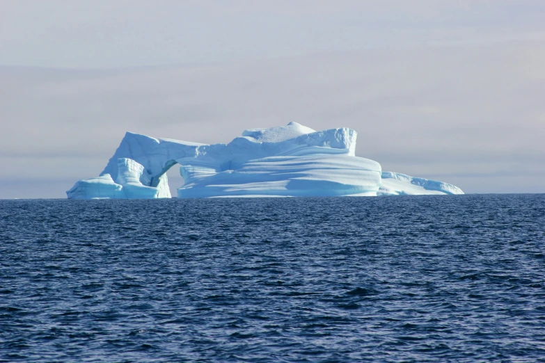 an iceberg sitting on the water next to a big body of water