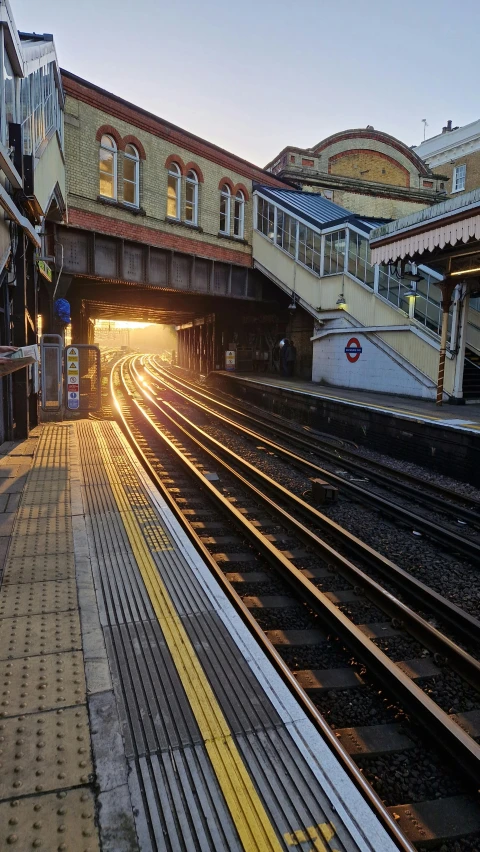 a train sits at a station while the sun is setting