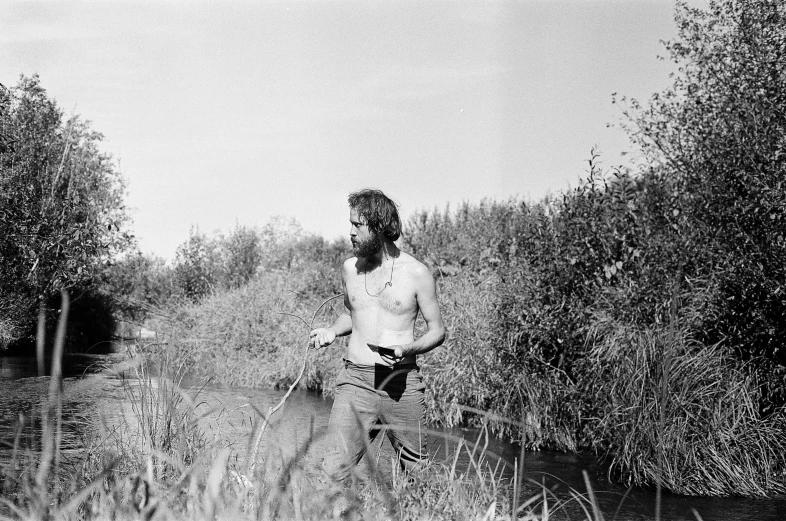 man walks alone in a field by the water