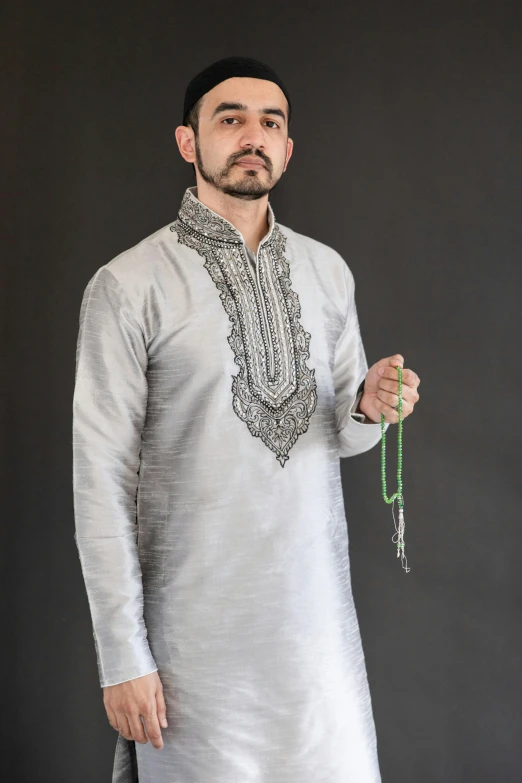 man in white linen outfit holding silver cross - chain