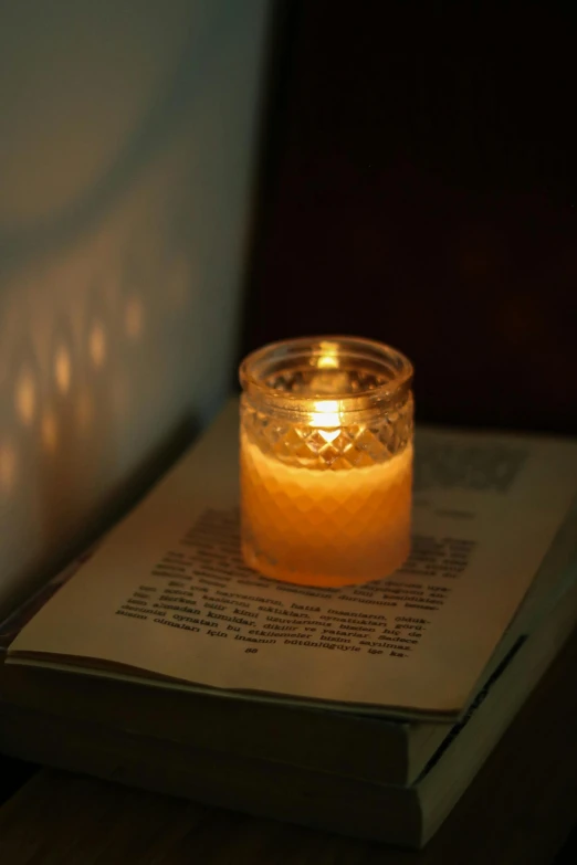 an open book with a lit candle on top of it