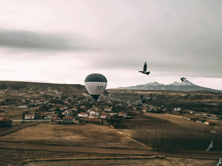 some people in  air balloons flying over buildings