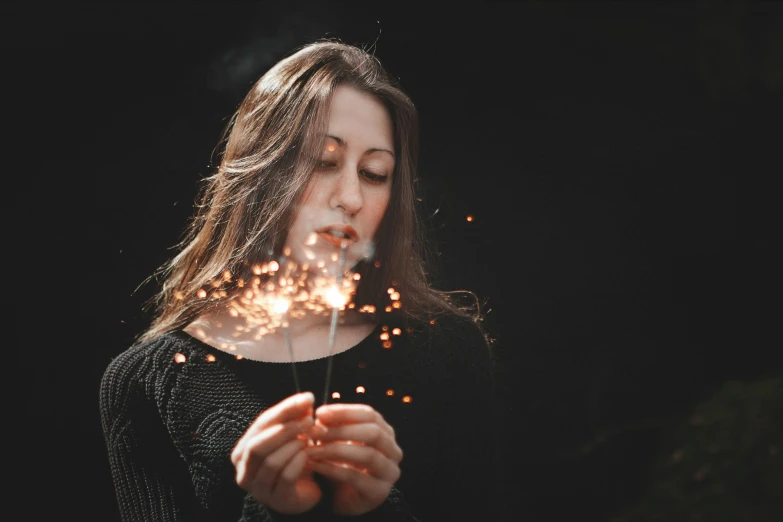 woman looking at sparklers that she is holding